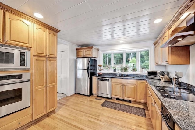 kitchen featuring sink, dark stone countertops, stainless steel appliances, wall chimney exhaust hood, and light wood-type flooring