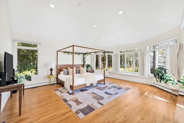 bedroom featuring a baseboard radiator, light hardwood / wood-style floors, and vaulted ceiling