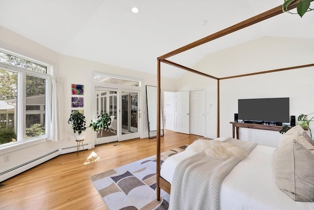 bedroom featuring light hardwood / wood-style flooring, a baseboard heating unit, and vaulted ceiling