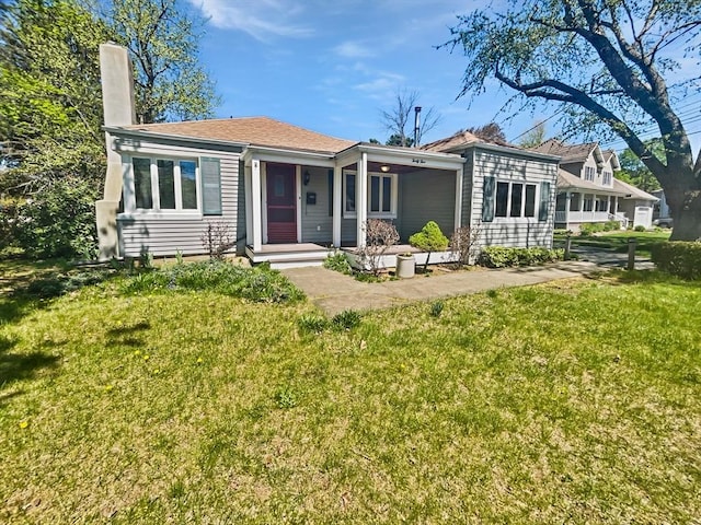 rear view of property with a yard, a chimney, and covered porch