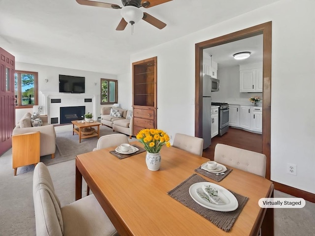 dining area with a ceiling fan, a healthy amount of sunlight, and a fireplace