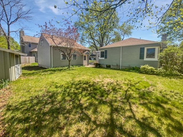 rear view of house featuring fence, an outdoor structure, and a yard