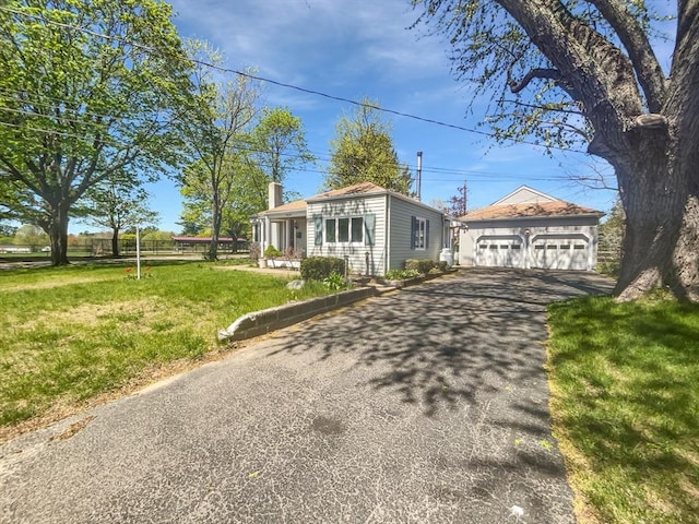 ranch-style house with driveway, a chimney, a garage, an outdoor structure, and a front lawn