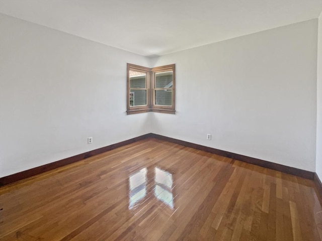 spare room with baseboards and wood finished floors