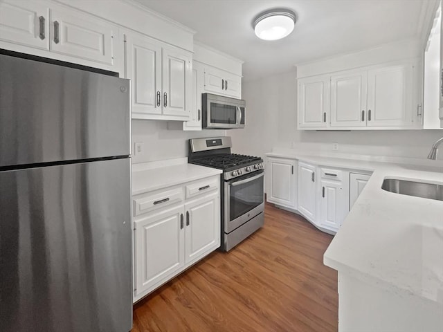 kitchen with light countertops, white cabinets, appliances with stainless steel finishes, and a sink