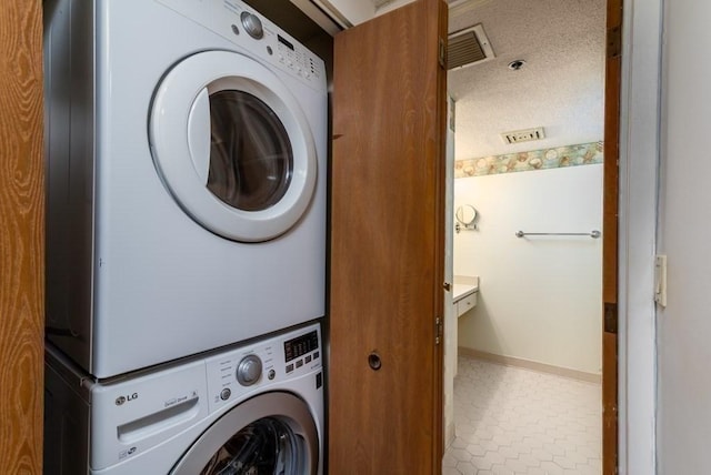 200 Burkhall Unit 103, Weymouth, MA 02190 - laundry room featuring stacked washer and clothes dryer, a textured ceiling, and tile patterned flooring