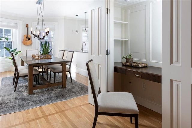 dining room with crown molding, sink, an inviting chandelier, and light wood-type flooring