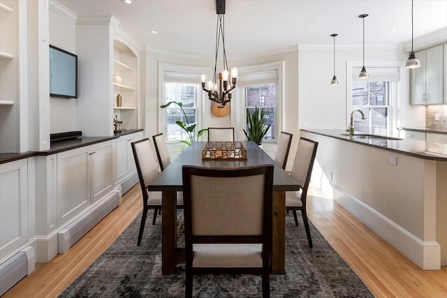 dining space with sink, light wood-type flooring, ornamental molding, and a baseboard heating unit