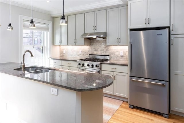 kitchen with dark stone countertops, sink, decorative light fixtures, and high quality appliances