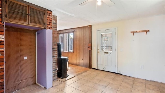 14 Maple St, Amesbury, MA 01913 - foyer entrance with a wood stove, ceiling fan, light tile patterned floors, and wood walls