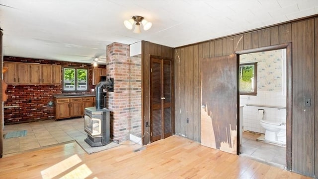 14 Maple St, Amesbury, MA 01913 - unfurnished living room featuring a wood stove, light wood-type flooring, and wood walls