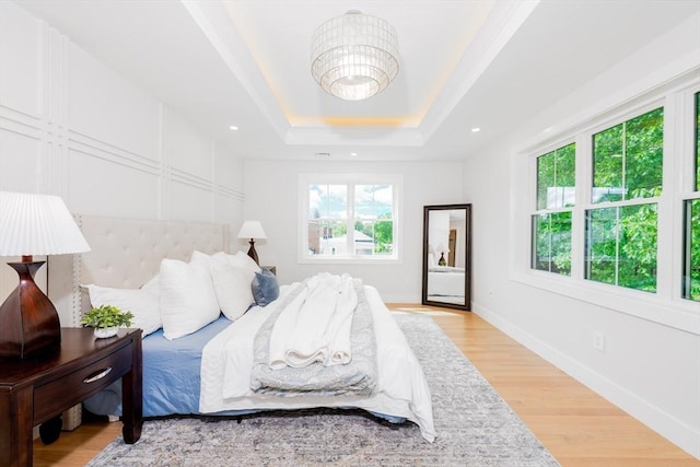 bedroom with a raised ceiling and light hardwood / wood-style floors