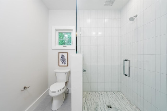 bathroom featuring a shower with door and toilet