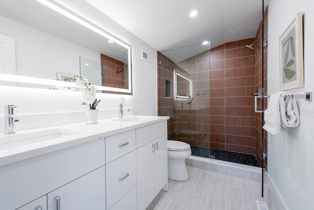 bathroom with vanity, toilet, lofted ceiling, and tiled shower