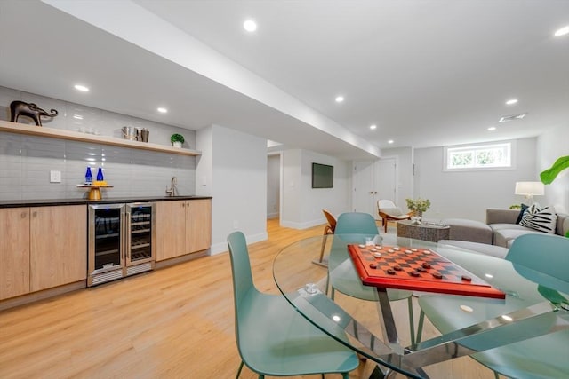 dining area featuring wine cooler, light hardwood / wood-style floors, and indoor wet bar