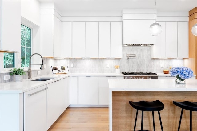 kitchen featuring backsplash, sink, decorative light fixtures, white cabinets, and stainless steel gas stovetop