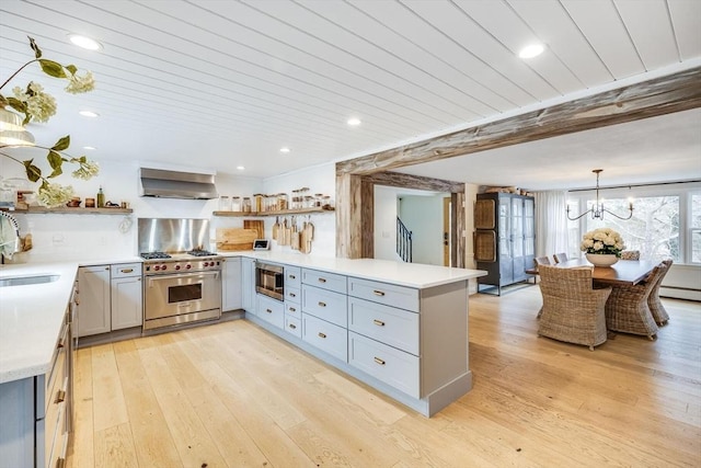 kitchen with a peninsula, wall chimney range hood, appliances with stainless steel finishes, and open shelves