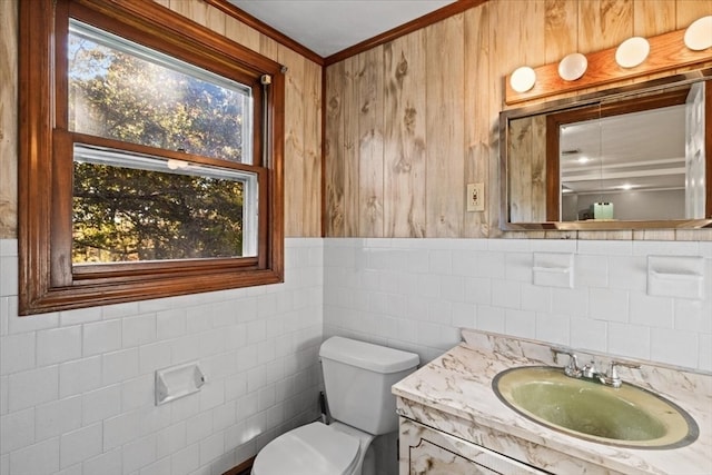 bathroom with vanity, toilet, crown molding, and tile walls