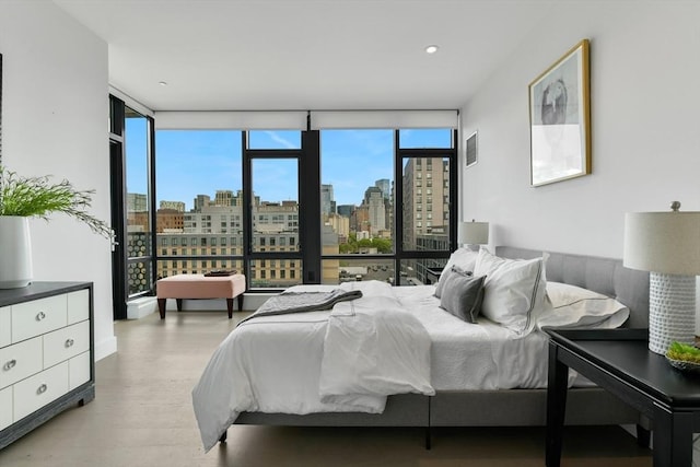 bedroom with expansive windows, a view of skyline, and light wood-style flooring