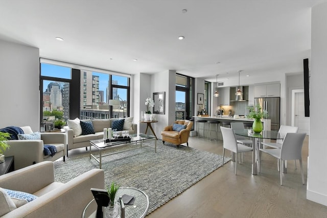 living area with a view of skyline, light wood finished floors, and recessed lighting