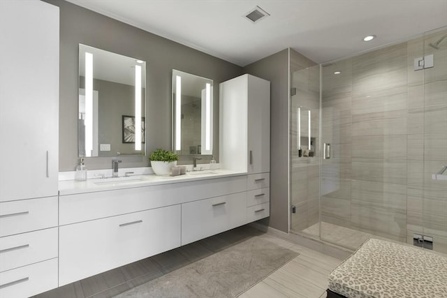 full bath featuring a stall shower, double vanity, and recessed lighting