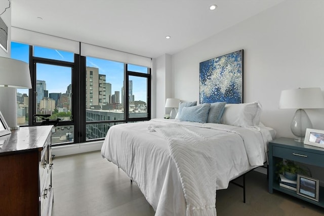 bedroom with multiple windows, a view of skyline, recessed lighting, and a wall of windows