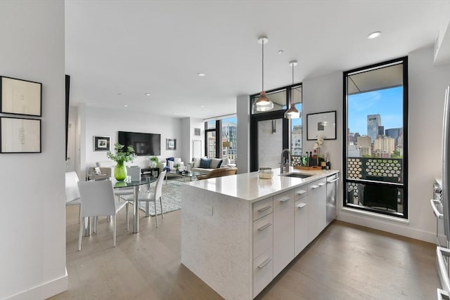 kitchen with modern cabinets, a sink, light wood finished floors, hanging light fixtures, and recessed lighting