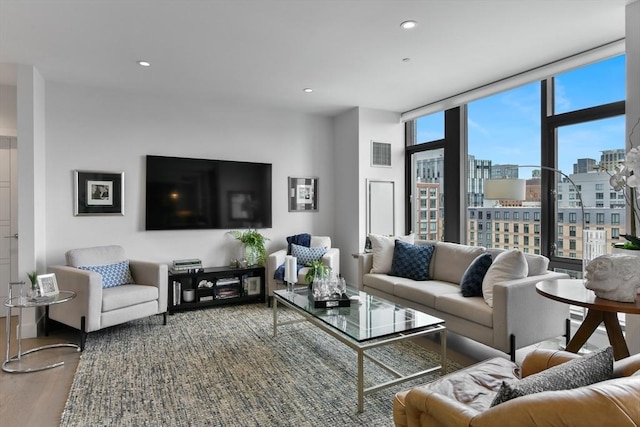 living area with a wall of windows, wood finished floors, and recessed lighting