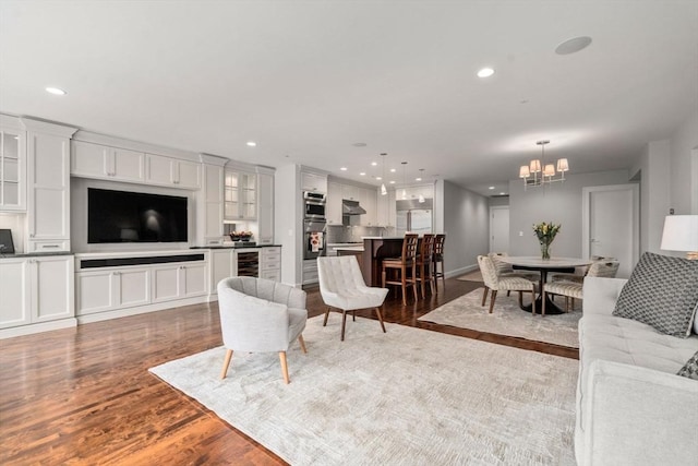 living room with a chandelier, wine cooler, wood finished floors, and recessed lighting