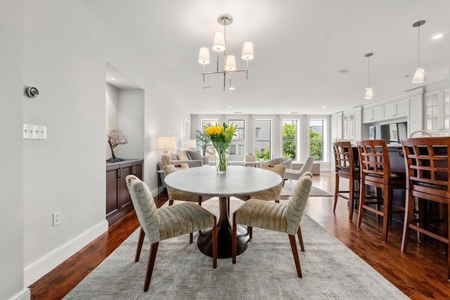 dining area featuring dark wood-style flooring, a notable chandelier, and baseboards