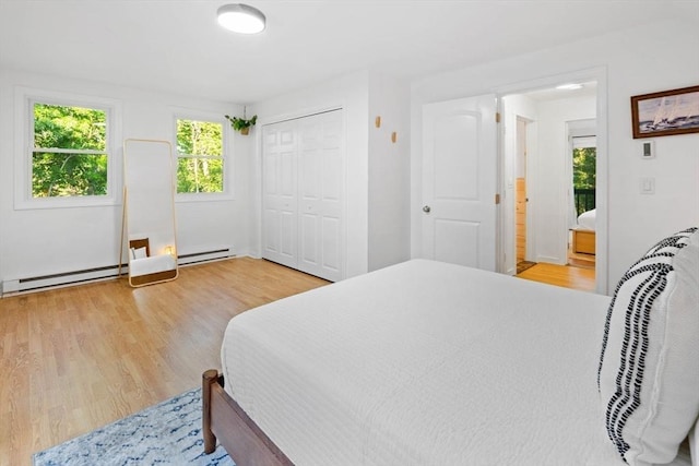 bedroom with a baseboard radiator, a closet, and light wood-type flooring
