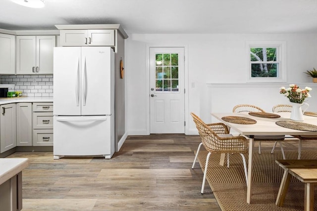 kitchen featuring tasteful backsplash, freestanding refrigerator, light wood finished floors, light countertops, and baseboards