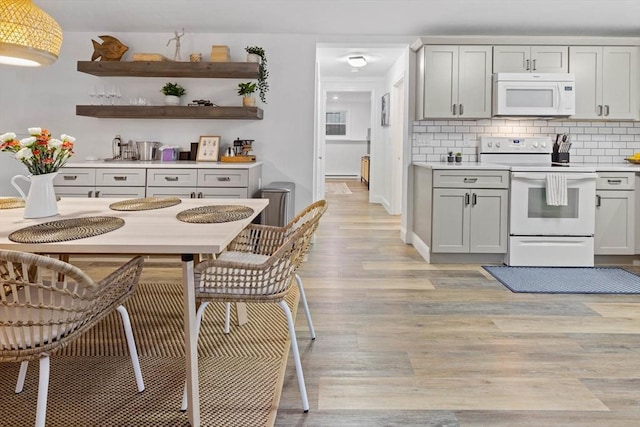 kitchen with light wood-style flooring, gray cabinets, white appliances, light countertops, and tasteful backsplash