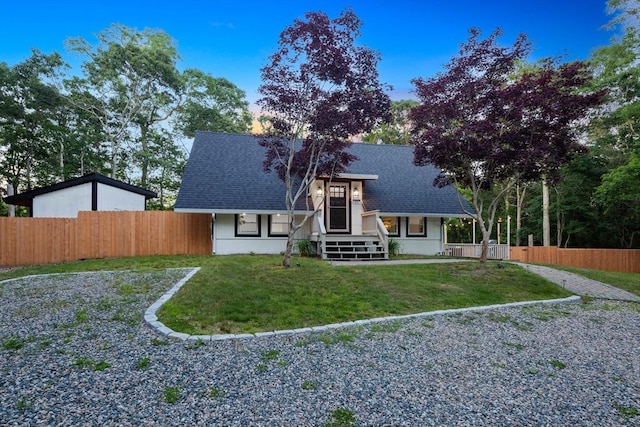 rear view of house featuring a yard, roof with shingles, and fence private yard