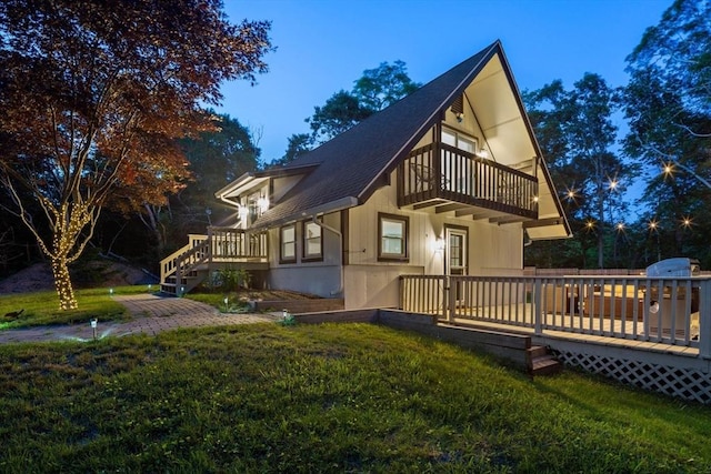 exterior space featuring a lawn, roof with shingles, a deck, and a balcony