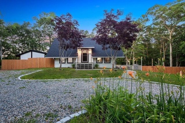 rear view of house featuring a lawn, roof with shingles, and fence
