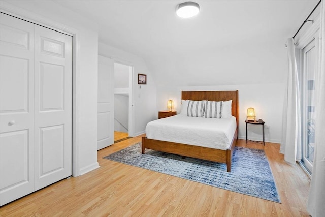 bedroom featuring lofted ceiling, baseboards, and light wood-type flooring