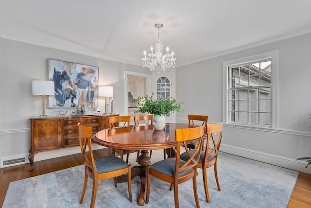 dining room featuring a chandelier, visible vents, baseboards, and wood finished floors