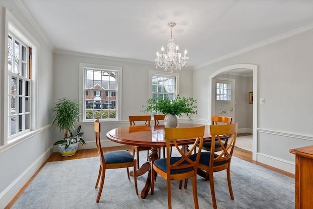 dining area featuring arched walkways, baseboards, wood finished floors, and a healthy amount of sunlight