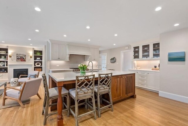 kitchen with light wood finished floors, a center island with sink, light countertops, and recessed lighting