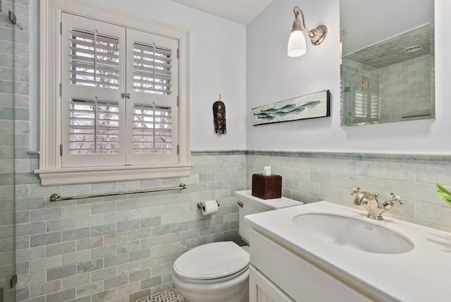 bathroom featuring a wainscoted wall, tile walls, toilet, a tile shower, and vanity