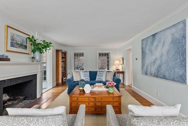 living area with a fireplace with flush hearth, ornamental molding, baseboards, and wood finished floors