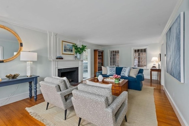 living area with a fireplace with flush hearth, wood finished floors, and crown molding