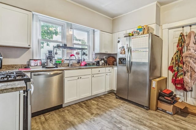 114 Chancery St, New Bedford, MA 02740 - kitchen featuring appliances with stainless steel finishes, ornamental molding, white cabinets, a sink, and light wood-type flooring
