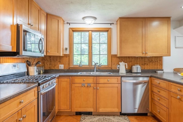 143 Davis St, Northborough, MA 01532 - kitchen with stainless steel appliances, a sink, dark countertops, light tile patterned floors, and brown cabinetry