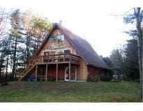 rear view of property featuring a wooden deck and a yard