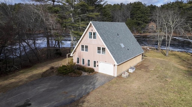 view of property exterior featuring a yard, a water view, and a garage