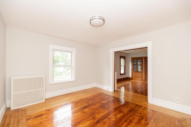 empty room with hardwood / wood-style floors and radiator heating unit