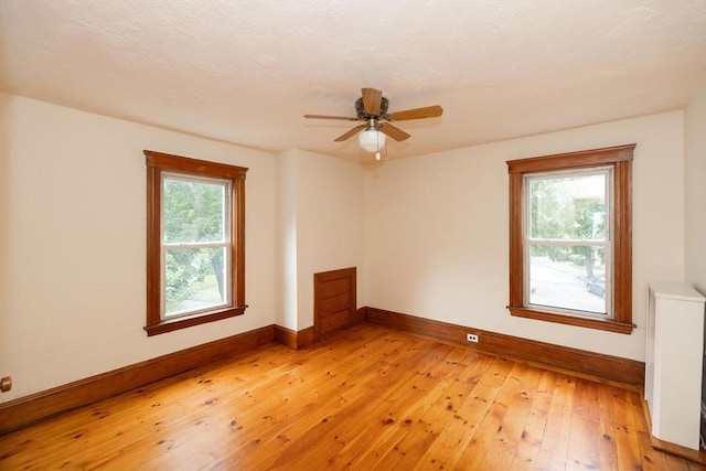 empty room with ceiling fan, light hardwood / wood-style floors, and a wealth of natural light