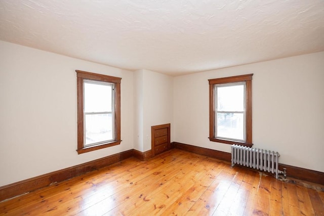 unfurnished room with radiator heating unit and hardwood / wood-style floors